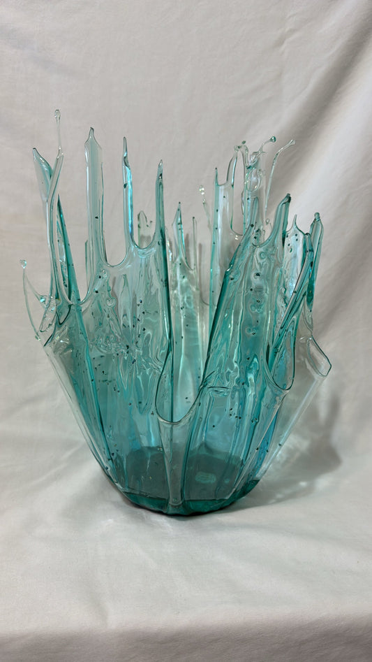 Turquoise glass vase with wavy design on a white background